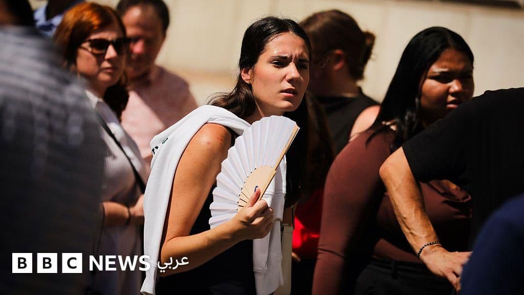 شخص يستخدم مروحة بجانب مكيف هواء في غرفة مكيفة